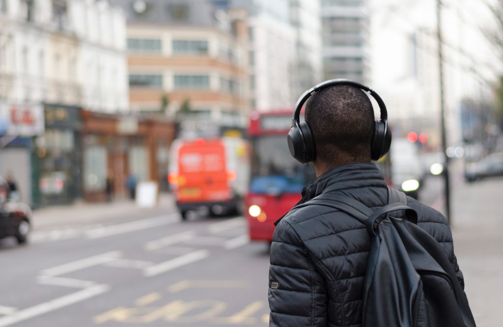 man walking on street listening to headphones