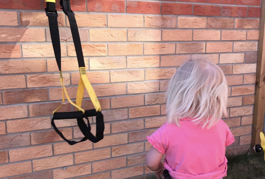 Girl using suspension trainers for a home workout.